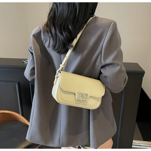 Detail of a creamy beige leather crossbody bag with a silver N-shaped metal buckle buckle