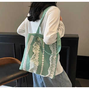 Close-up of green vichy plaid tote bag with intricate white lace details and ruffles