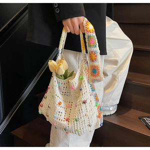 Makroaufnahme der weißen Häkeltasche mit bunten Perlen und geblümten Griffdetails