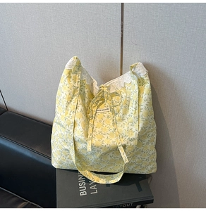 Détail d'un cabas floral avec motif jaune, bordure en dentelle et étiquette interne