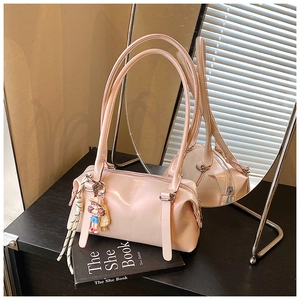 Pink glossy pillow bag on black books featuring a cute cartoon charm and shoulder strap