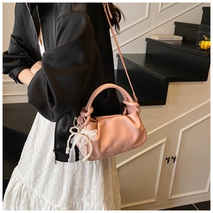 Detalle del bolso de cubo plisado rosa con colgante de perlas y encaje suave