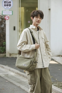 Close-up of olive nylon dumpling bag with adjustable strap and front zipper pocket