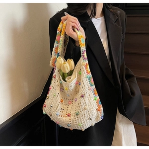 Detail der cremefarbenen Häkeltasche mit bunten Perlen und gehäkeltem Schultergurt mit Blumen