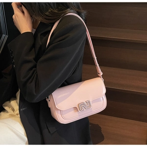 Pink patent leather shoulder bag with silver metallic lock on model in black suit
