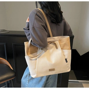 Detail van de tweekleurige canvas shopper met leren handvatten gedragen op de schouder