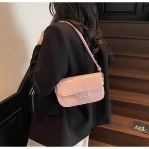 Detailed side view of a glossy pink shoulder bag with a silver N-shaped metal buckle