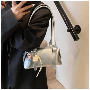 Metallic silver rectangle shoulder bag with cute charms and double handles on a black suit
