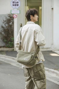 Macro view of olive green waterproof nylon crossbody bag showing premium stitching texture