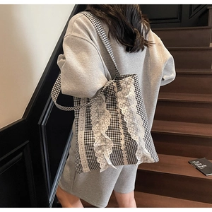 Detailed view of white lace ruffles on a black and white checkered tote bag
