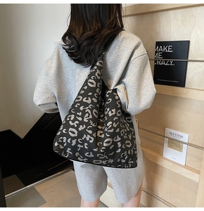 Vista detallada del bolso tote grande con estampado de leopardo y fondo de estantería de madera