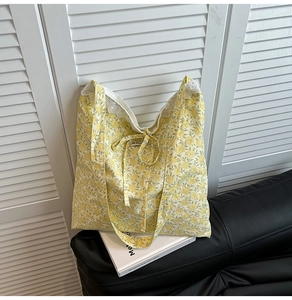 Détail du sac cabas en toile à fleurs jaunes avec dentelle blanche et nœud coulissant
