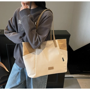Detailopname van grote canvas shopper met leren bies en QZBG-logo op de schouder gedragen