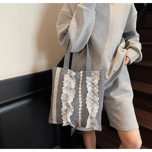 Close-up of black and white checkered tote bag featuring white lace and ruffle details
