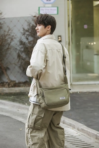 Detail of army green nylon messenger bag with adjustable strap and brand woven label