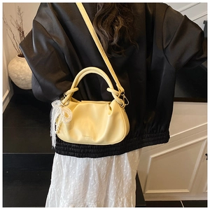 Detalle del bolso de cubo plisado amarillo con grabado en cuero y dije de perlas