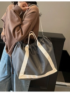 Large dark grey nylon tote bag with drawstring closure and off-white woven straps