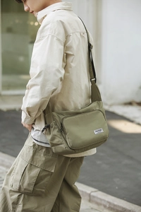 Detail of adjustable shoulder strap and zipper pocket on green nylon dumpling bag