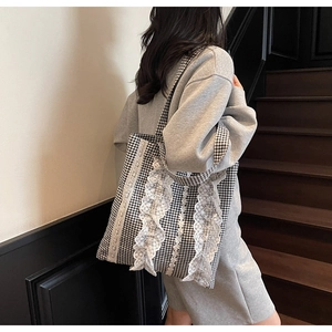Detail of white lace trims and ruffles on a black and white gingham tote bag