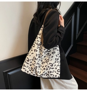 Detalle de un bolso tote grande de lona con estampado de leopardo y asas marrones