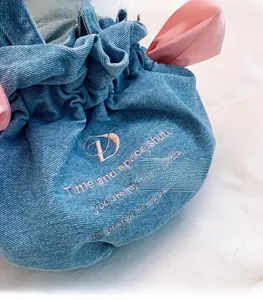 Gros plan d'un sac seau en jean avec broderie rose et grand nœud en ruban satin