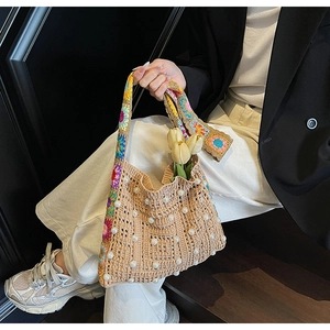 Detail der gewebten Strohtasche mit Perlen und buntem Schultergurt mit Blumenmuster