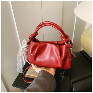 Detalle de bolso saco rojo plisado de piel sintética suave con colgante de perlas