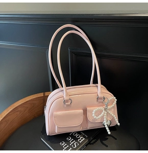 Close-up of pink glossy pillow bag with pearl bow charm and heart metal pendant