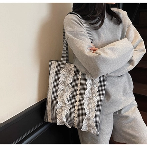Detailed close-up of a black and white gingham tote bag with delicate lace trimmings