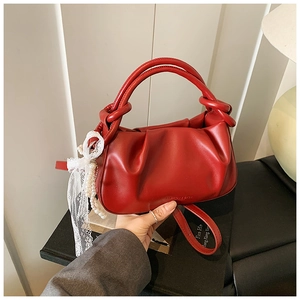 Detalle del bolso tipo cubo rojo plisado con asa trenzada y dije de perlas