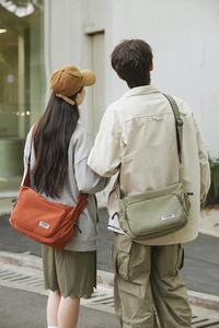 Detail of waterproof nylon dumpling bag in orange and green with wide shoulder strap