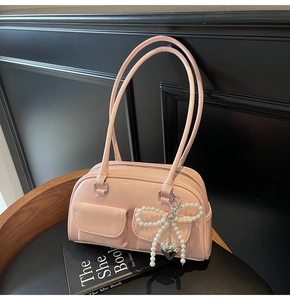 Detail of pink half-moon shoulder bag with pearl bow charm and heart metal pendant