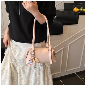 Pink rectangular shoulder bag with doll and ice cream pendant shown on a model's arm
