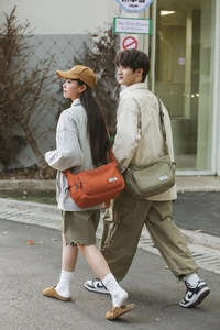 Outdoor shot of stylish waterproof nylon crossbody bags in orange and green colors