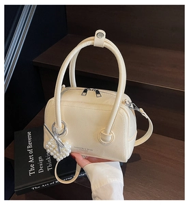 Detail of cream white leather pillow bag with heart pearl charm and silver zipper