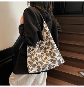 Vista detallada del bolso tote de lona con estampado de vaca usado por modelo