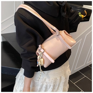 Pink cylinder shoulder bag with a cute bear charm shown on a stylish model