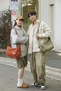 Outdoor lifestyle shot of large nylon dumpling messenger bags in orange and green