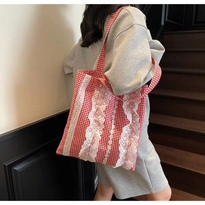 Detailed view of red and white gingham canvas tote bag with elegant white lace ruffles