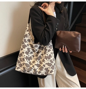 Detalle del bolso tote de lona con estampado de vaca y estuche marrón en una modelo
