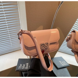 Detailed view of pink patent leather crossbody bag with silver geometric buckle