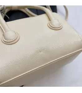 Close-up of beige shiny PU leather boston bag with elegant silver lettering detail