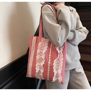 Detailed close-up of a red gingham tote bag with delicate white lace trim and ruffles