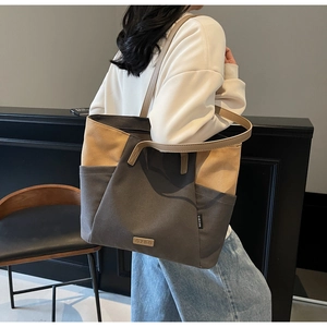 Detailweergave van grote canvas tote bag met kleurblokken en luxe leren schouderbanden