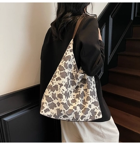 Detalle del bolso tote de lona con estampado de vaca y correas de cuero marrón