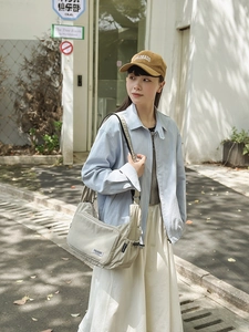 Asian model wearing a large beige nylon shoulder bag in an outdoor street setting