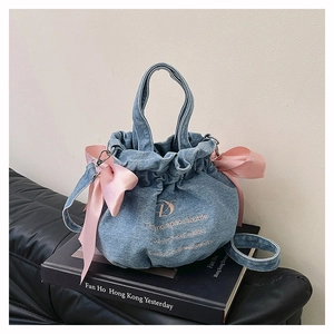 Vue détaillée du sac seau en denim avec nœuds en satin rose et broderie dorée