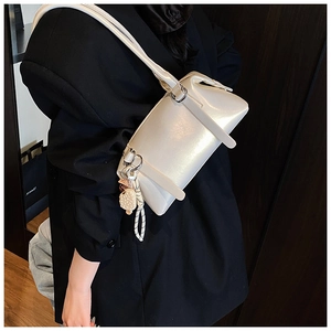 Detail of pearl white leather shoulder bag with waffle charm on black blazer model