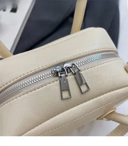 Detail of silver dual metal zippers on off-white pebbled leather handbag with rectangular pulls