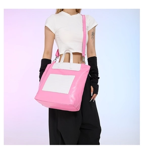 Detail of pink and white faux leather tote bag with silver metal hardware and top handles